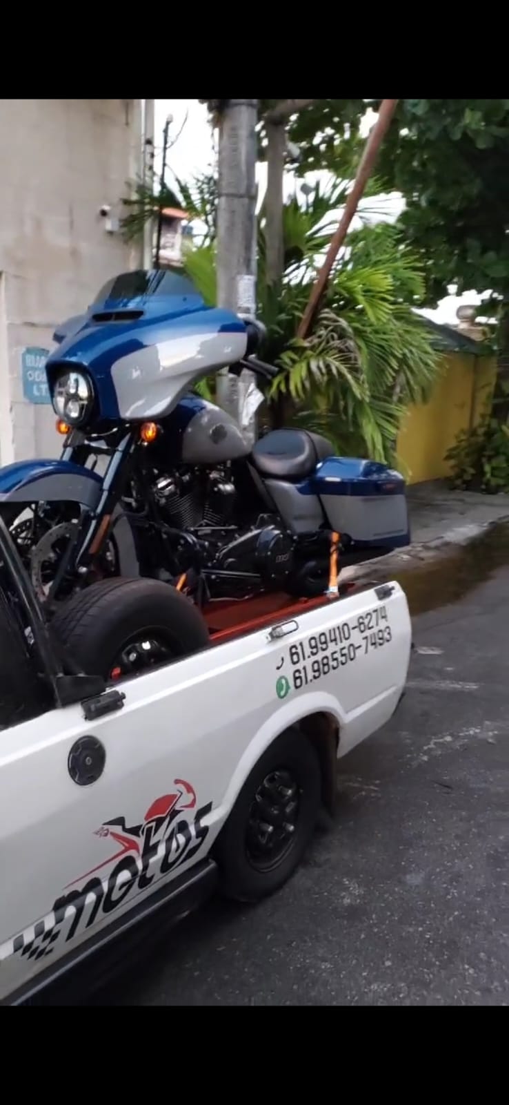 Moto esportiva coberta com capa sendo transportada em dia de chuva na estrada
